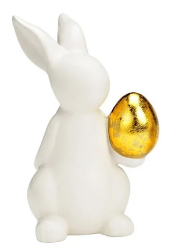 Valkoinen pupu, iso, kullanvärinen muna kädessä